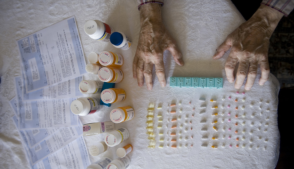 Overhead Shot Of A Table With Prescription Pills Laid Out and Ready To Be Doled Out In Pill Organizer With Elderly Gentleman's Hands On One Side, My Father Won't Take His Meds 