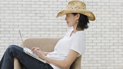 Mujer con sombrero vaquero escribiendo en un computador portátil