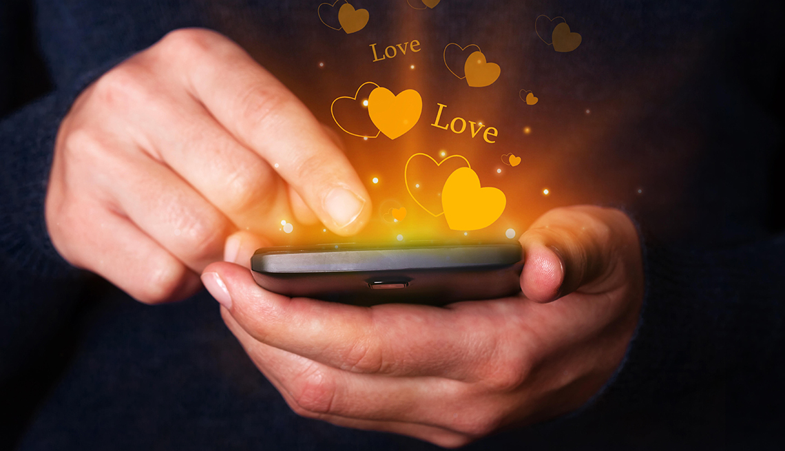 Woman hands holding and using smartphone mobile or cell phone for texting or messaging with hearts and love bubbles coming out of the phone