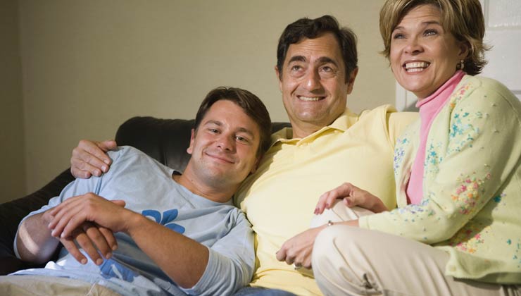 Familia sentada en un sofá y sonriendo - ayudar a las familias a apoyar a un miembro de la familia con discapacidad