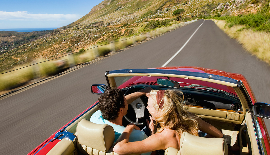 A couple in a convertible on a scenic highway