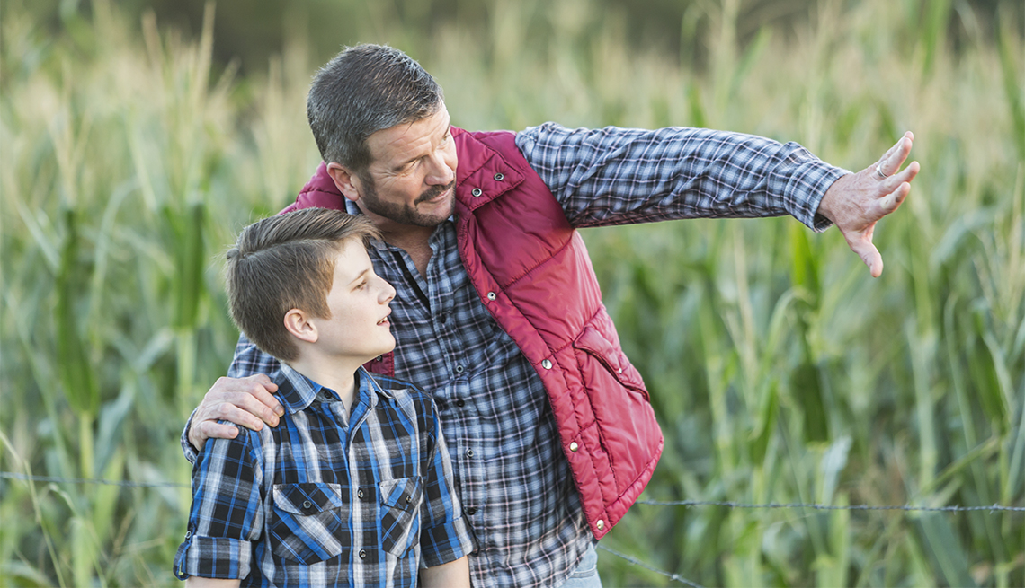 Un agricultor con su hijo, de 13 años de edad, de pie en un campo de cultivos.