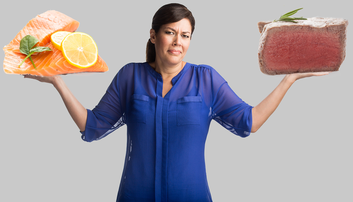 item 8 of Gallery image - Woman shrugging  arms, steak in one hand, salmon in the other