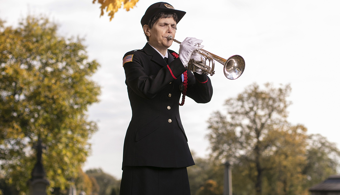 A woman plays a bugle at a military funeral