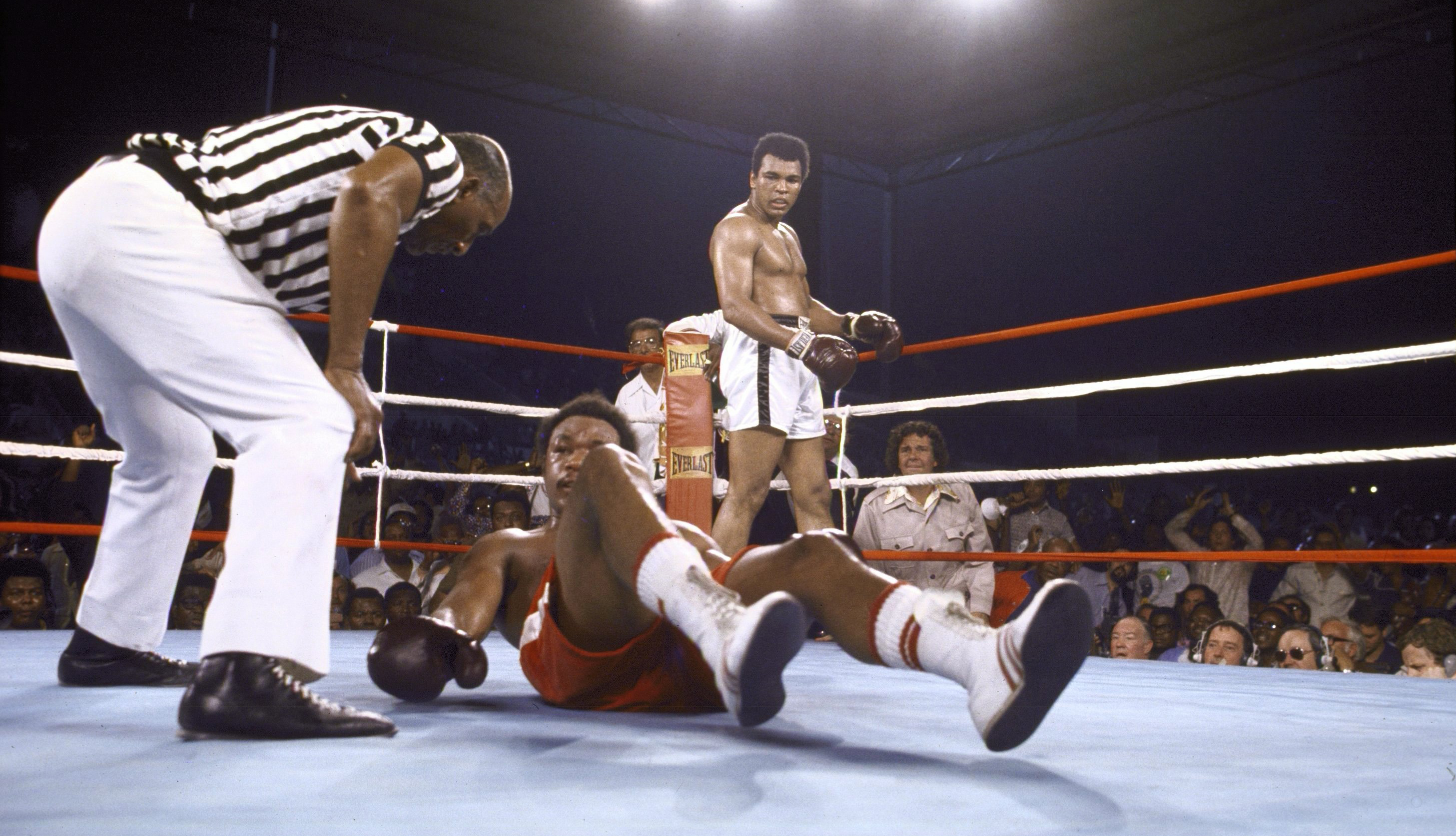 George Foreman tries to get off the canvas as referee Zack Clayton checks on him during the match against Muhammad Ali at 20th of May Stadium. Kinshasa, Zaire 10/30/1974 
