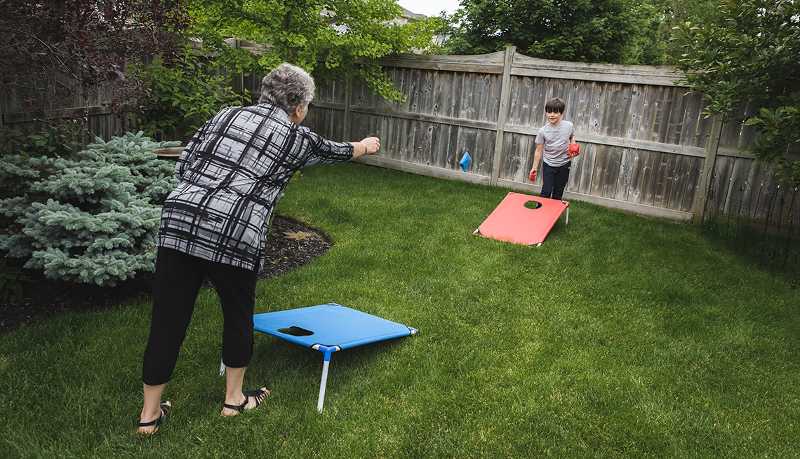 item 2 of Gallery image - woman playing cornhole with grandson in a fenced yard