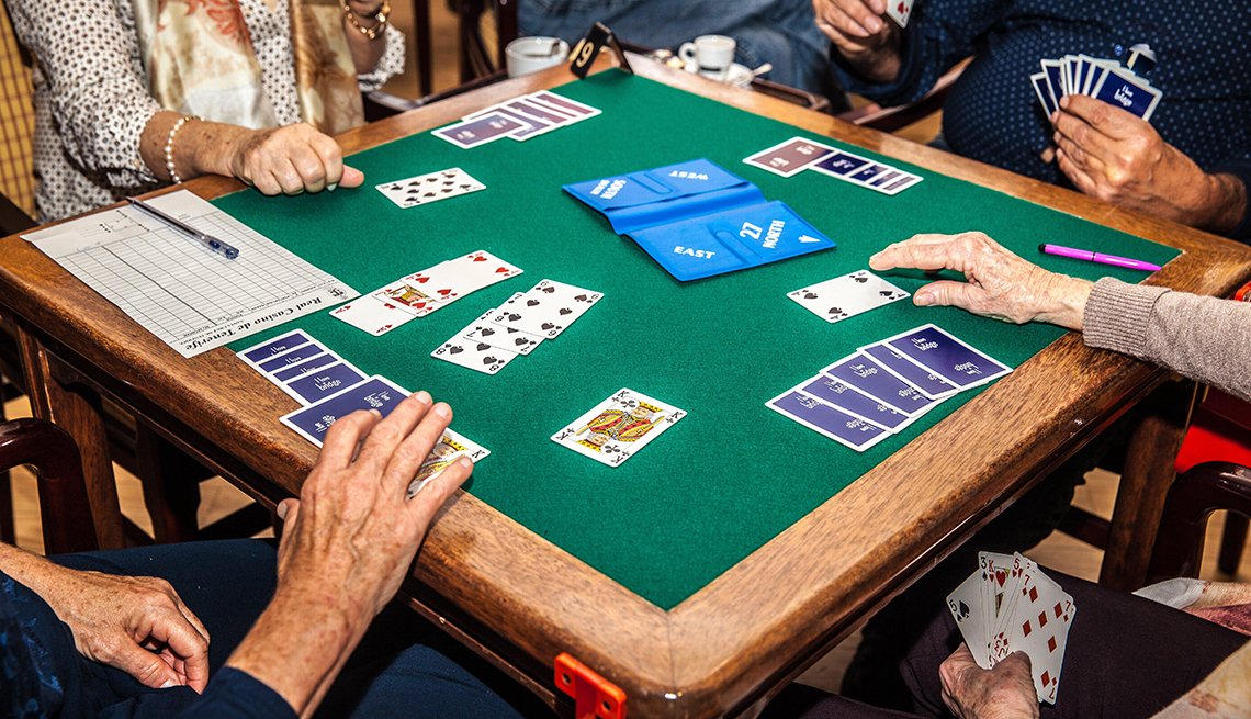 Adults gathered around a table playing the bridge card game