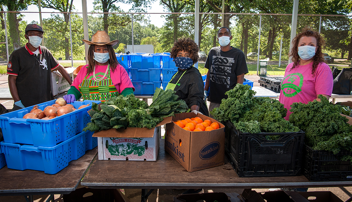La doctora Cindy Ayers Elliott y sus empleados de la granja están parados con mascarilla detrás de una mesa llena de productos