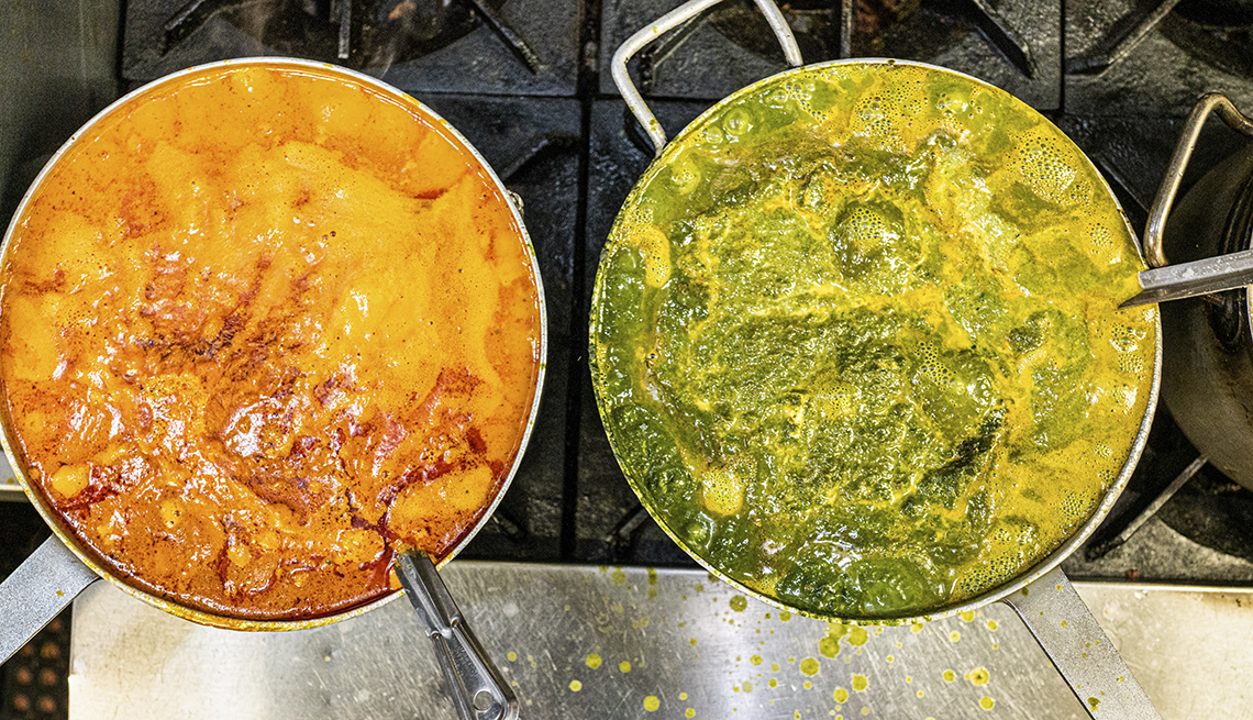 two indian food sauces simmer on a restaurant stove as seem from above
