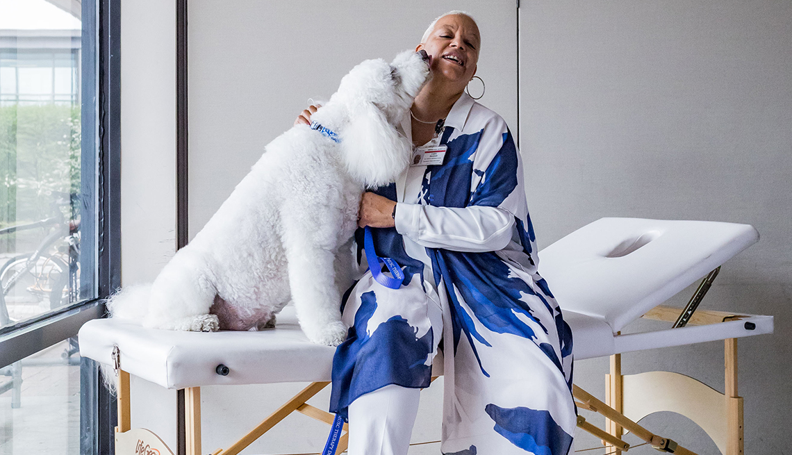 item 6 of Gallery image - woman sitting on massage table hugging a big poodle dog