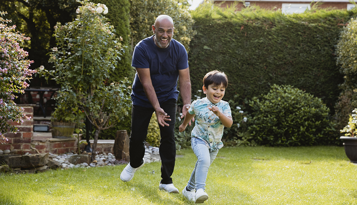 Abuelo persiguiendo a su nieto en el jardín mientras juegan al aire libre