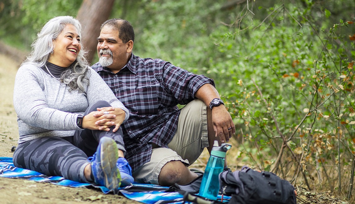 A couple enjoying a picnic on a blanket in the woods.