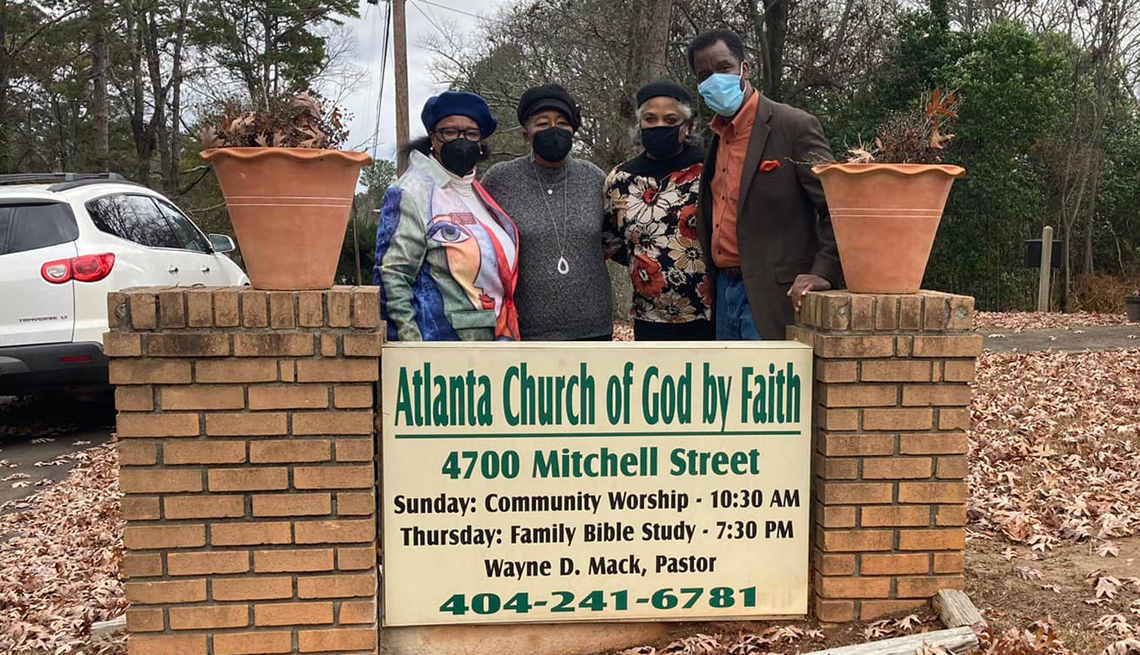 pastor wayne mack and others stand in front of the atlanta church of god by faith sign