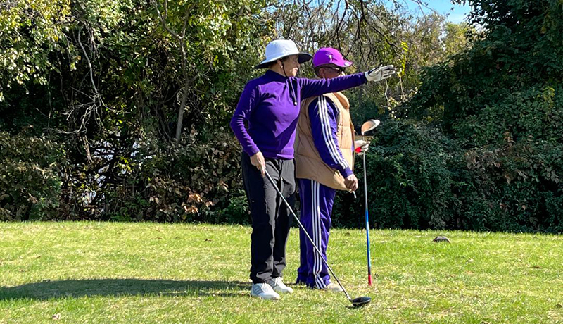 two women golfers one is pointing out to the distance while the other looks that way