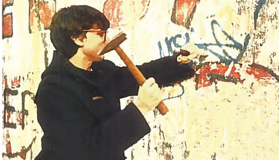David Patton martillando un trozo del Muro de Berlín