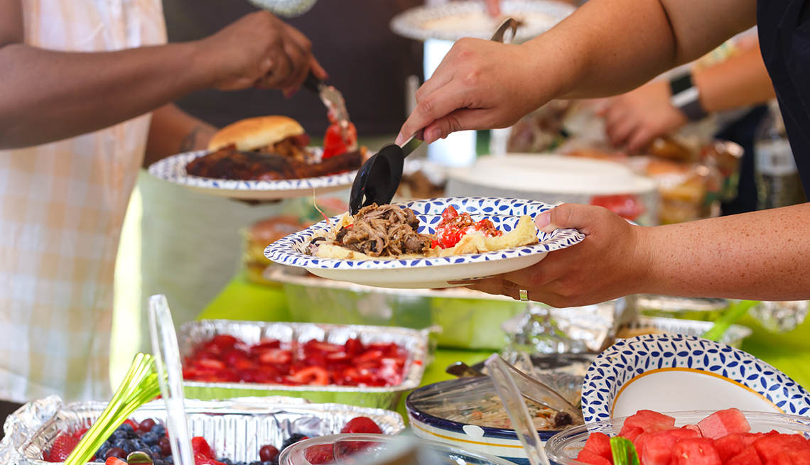 guests filling plates with barbeque and fruit at a casual summer cookout 