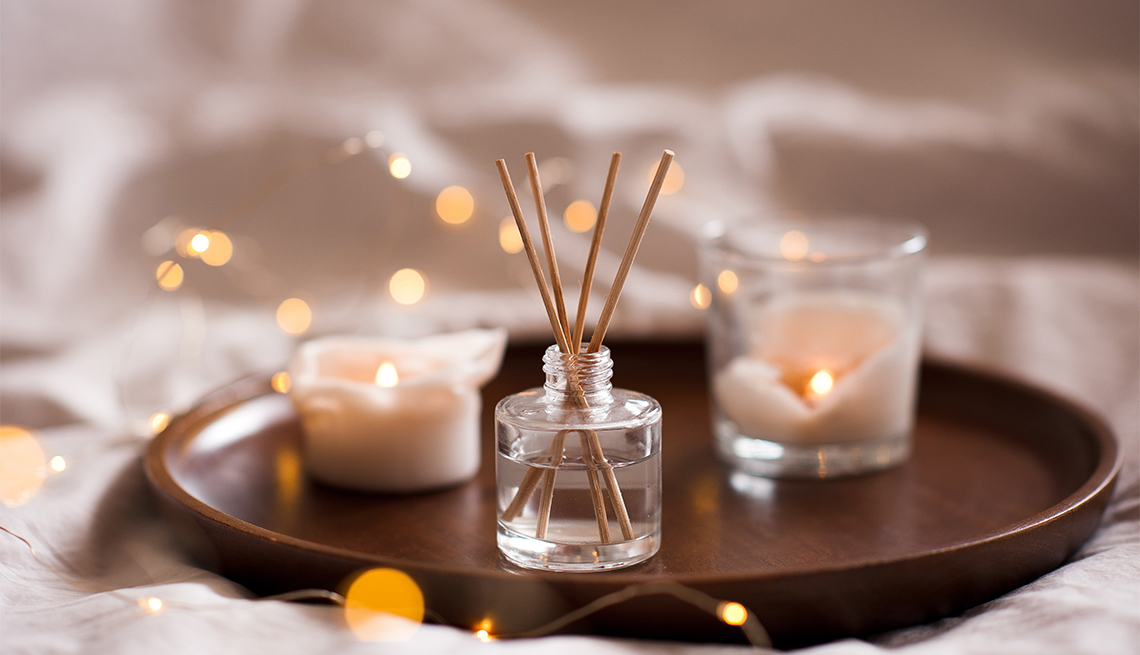 Perfume casero en botella de vidrio con palos de madera y velas