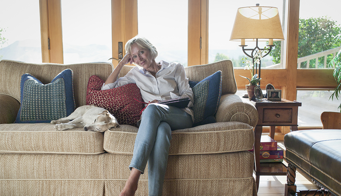 Mujer está sentada en un sofá con su perro