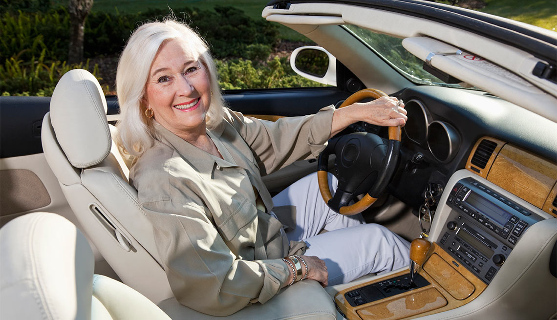 Happy woman with hand on steering wheel in convertible