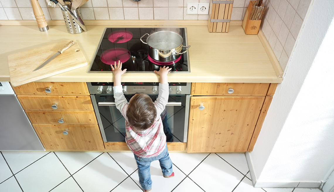 El pequeño niño se coloca cerca de una estufa, 10 consejos para prevenir accidentes en el hogar.
