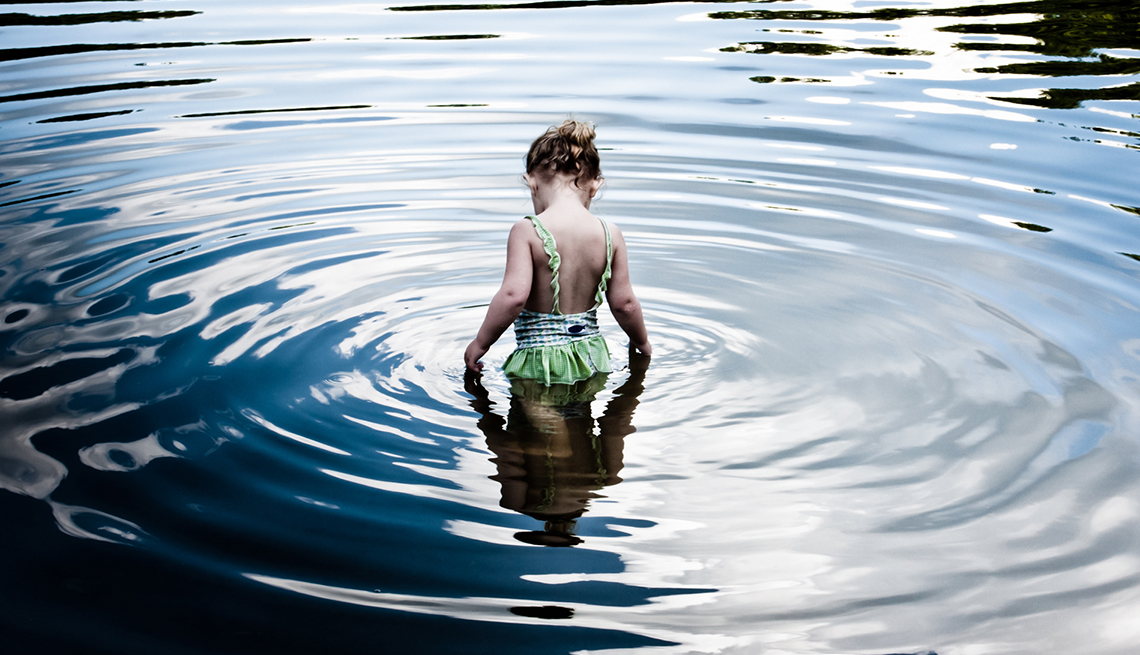 Young girl wading in a river.
