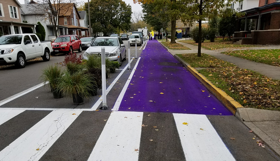 item 1 of Gallery image - a residential road with a purple painted bike lane and crosswalk is shown