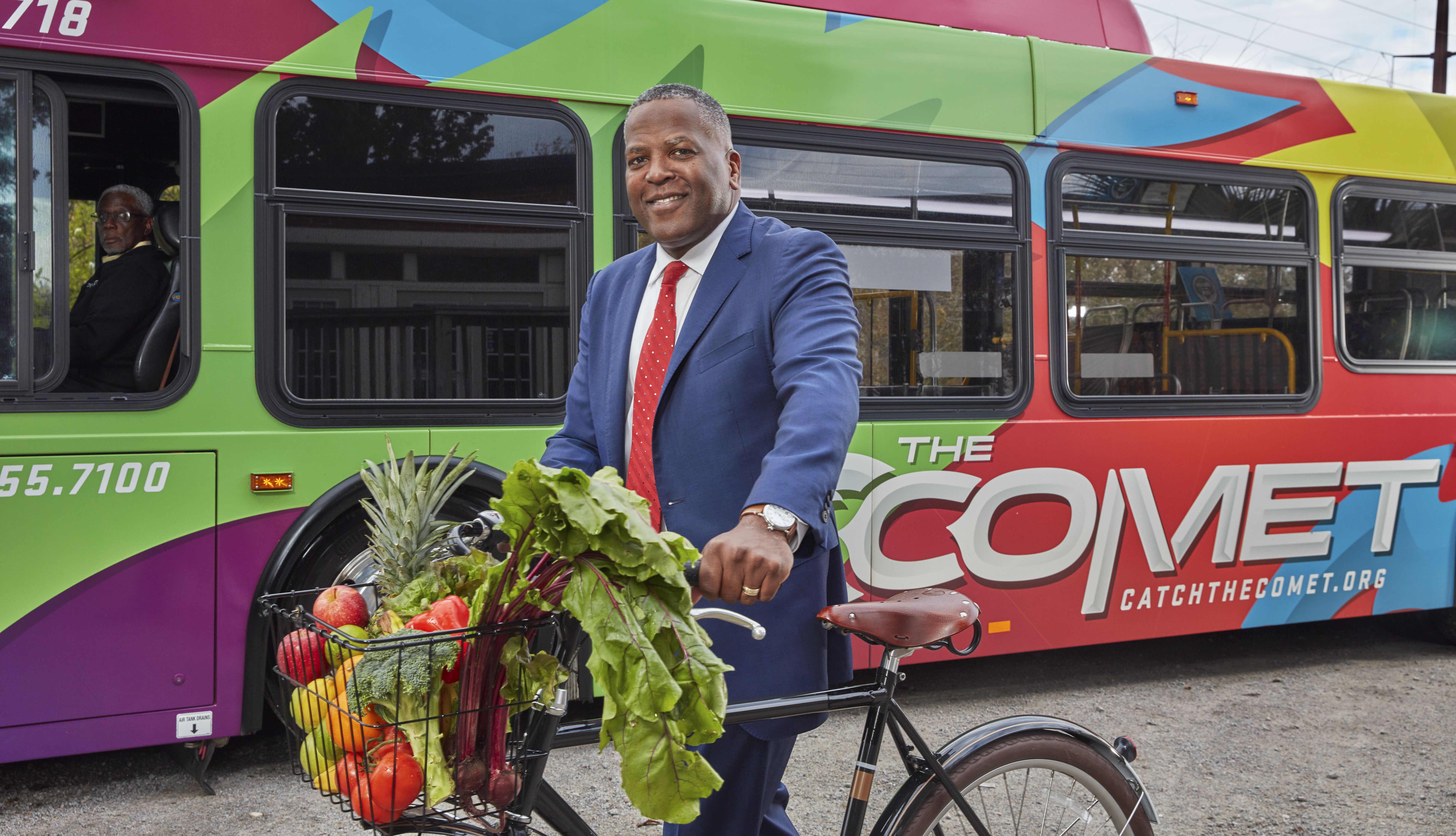 El alcalde de Columbia, Steve Benjamin, posa con una bicicleta frente a un autobús