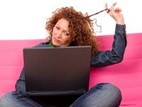 Enriquezca sus conocimientos en línea - Mujer viendo la pantalla de un computador que sostiene en las piernas.