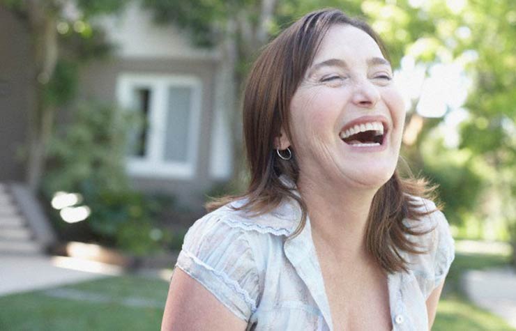 Mujer de pie al aire libre riendo, Espiritualidad: 5 claves para ayudarle a dejar de lado la negatividad