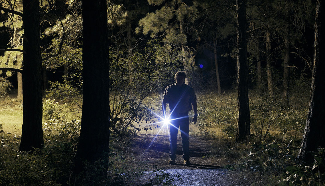 Man Holds Flashlight In Forrest At Night, AARP Holme And Family, Personal Technology, 13 Items That Have Been Replaced By The Smartphone