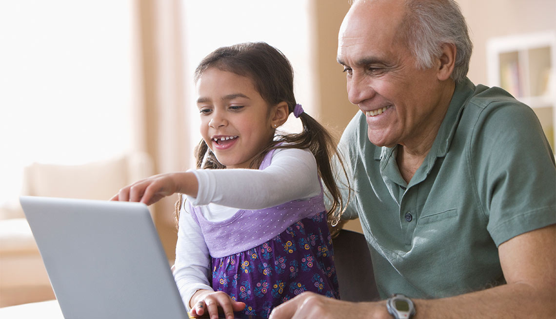 Abuelo con su nieta frente al computador - Cómo ayudar a tus nietos a tener una buena experiencia con la tecnología