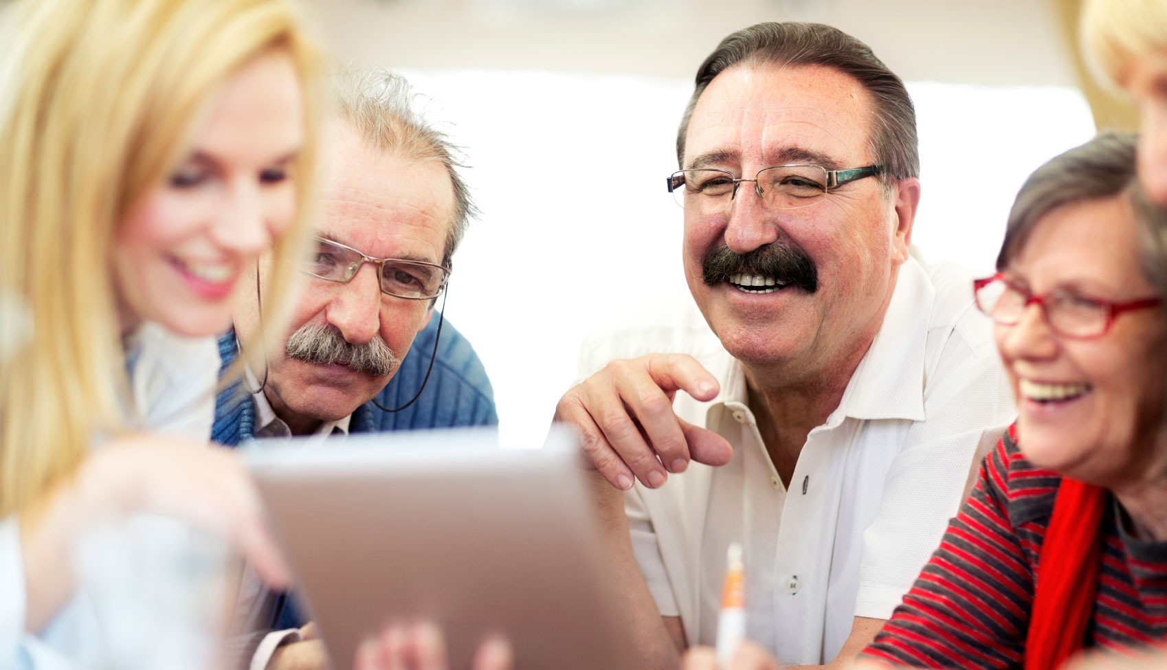 Adultos mayores observan una tableta electrónica