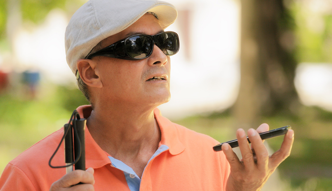 Hombre con discapacidad visual utilizando las funciones de asistente digital y facilidad de acceso en el teléfono móvil.