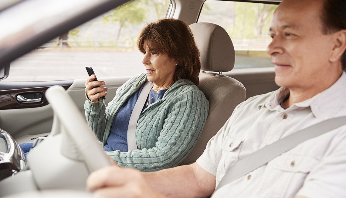 Mujer pasajera observa el GPS en el teléfono durante un viaje en automóvil