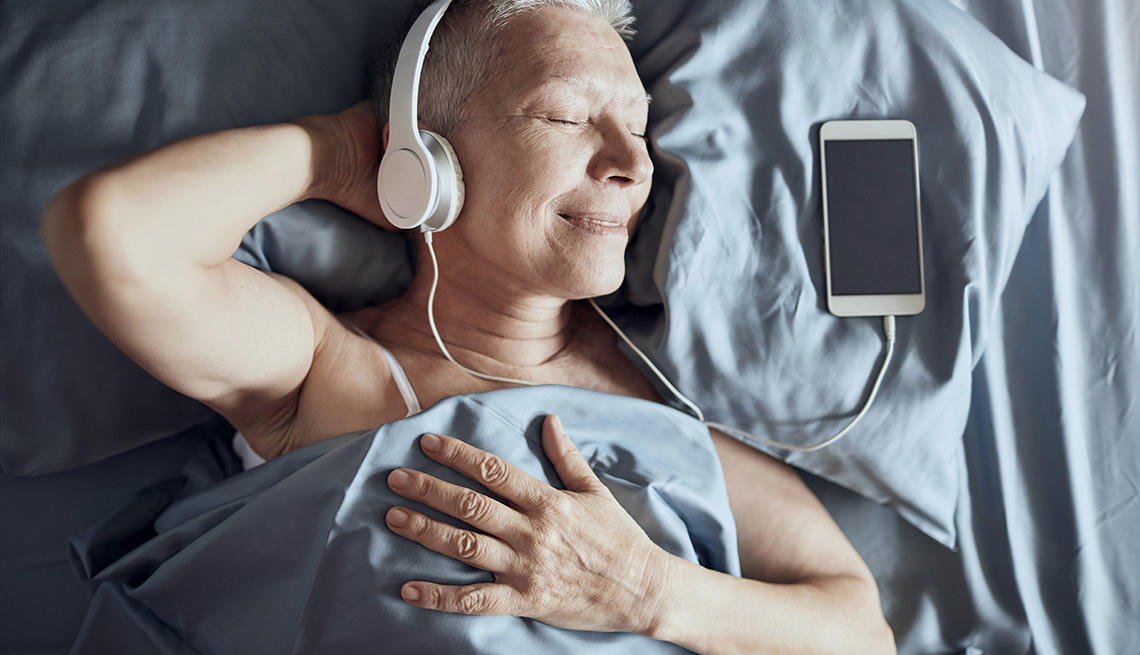 Una señora mayor escuchando música mientras está acostado en la cama