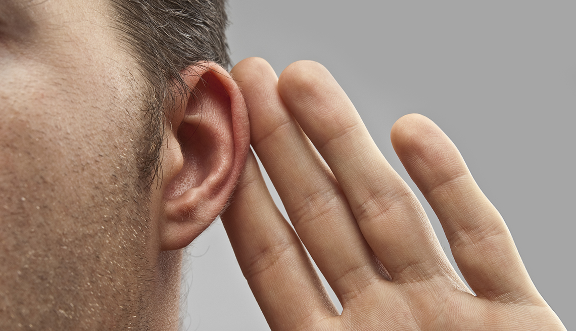 Vista cercana de un hombre que lleva sus dedos a la oreja haciendo un gesto de escuchar