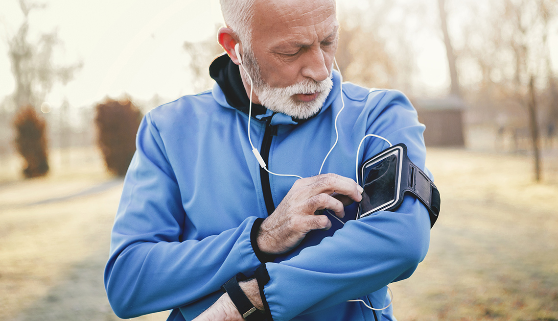 Older male checks his smartphone for missed call while jogging.