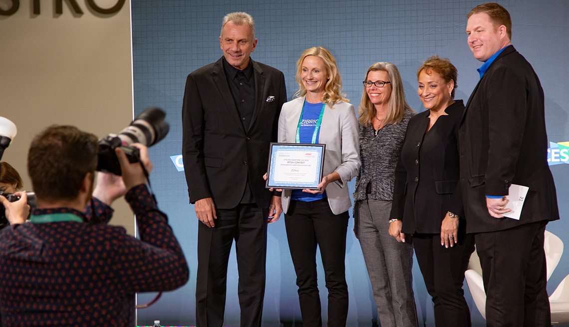 The winner of AARP's Innovation Pitch Contest,  CEO Jo Ann Jenkins and Joe Montana all pose on stage for a photograph