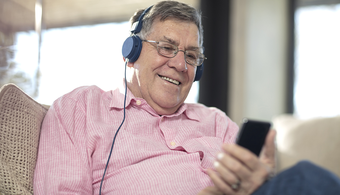 Un hombre con auriculares, escuchando música en el sofá