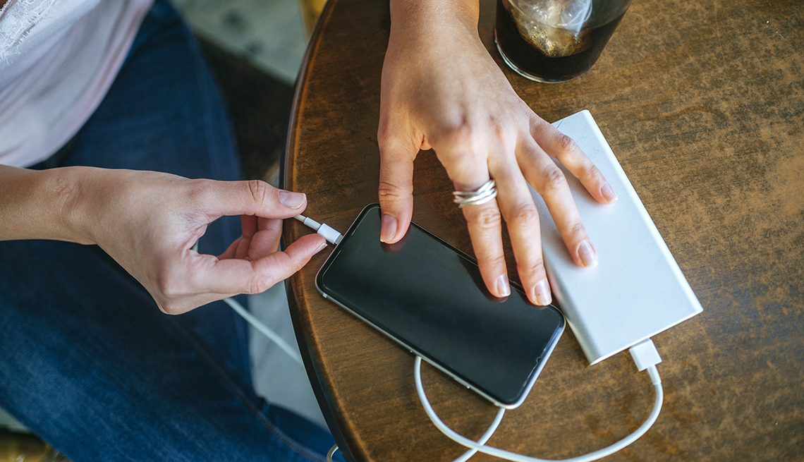 Close-up of Woman's hands plugging a mobile phone into a power bank  in a bar