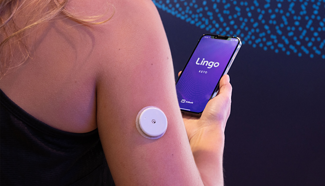 a woman wearing a lingo device that connects to an app to measure health data such as glucose and keto levels