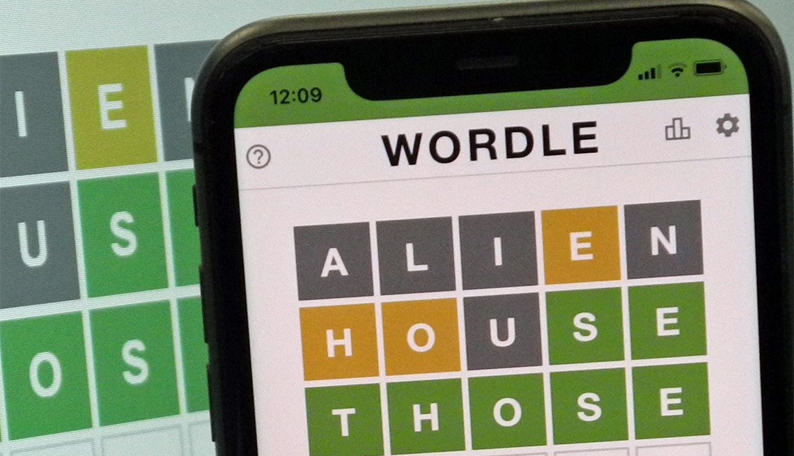 A mobile phone shows the screen of the popular online game Wordle 