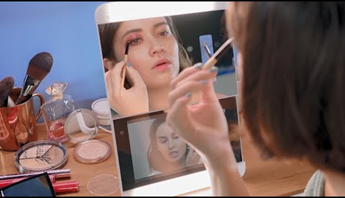 a young woman uses a smart mirror to apply make-up