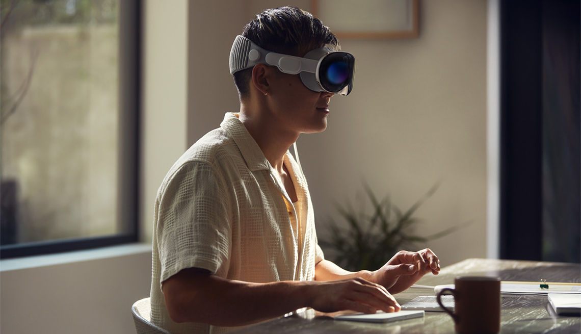Un hombre usando el casco de realidad virtual Apple Vsion Pro mientras escribe