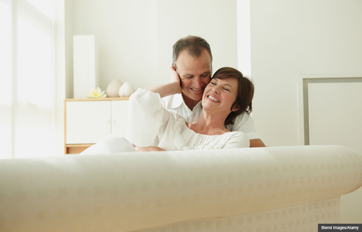 Couple cuddling together on sofa. A guide to sex after breast cancer. (Blend Images/Alamy)