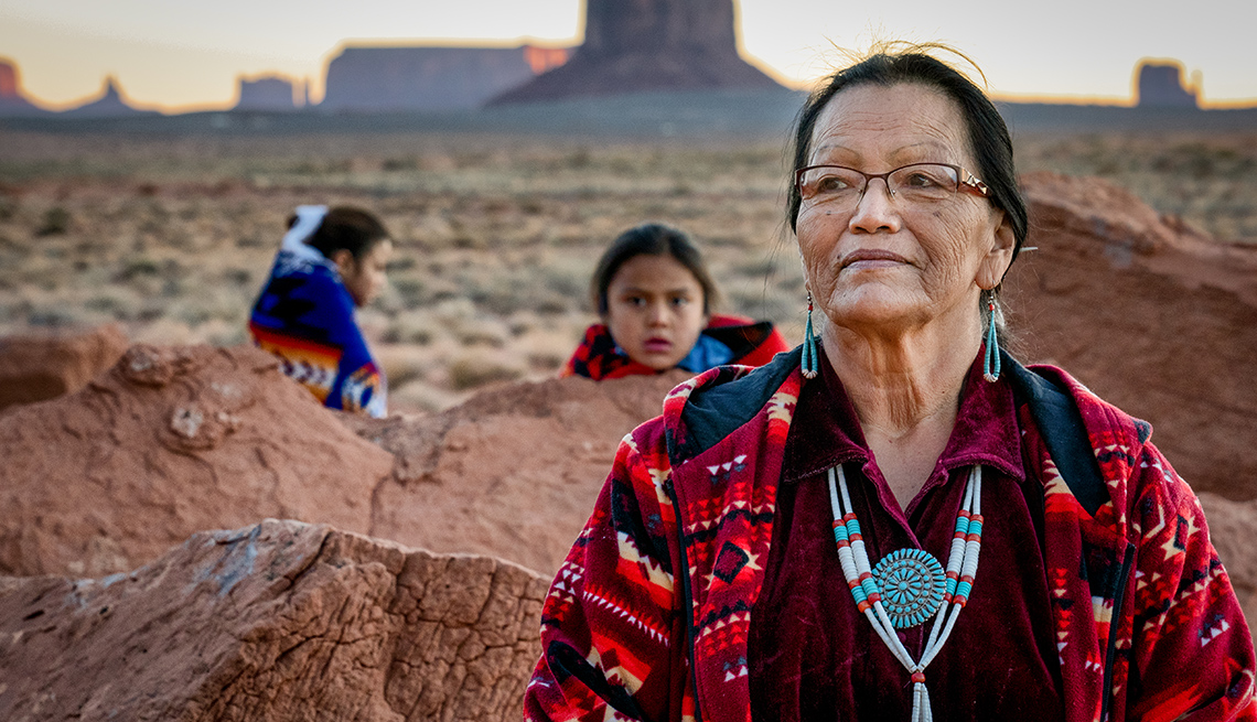 Portrait of a traditional Navajo grandmother with her grandson and granddaughter in front of the famous rock formations of the Monument Valley Tribal Park in Northern Arizona