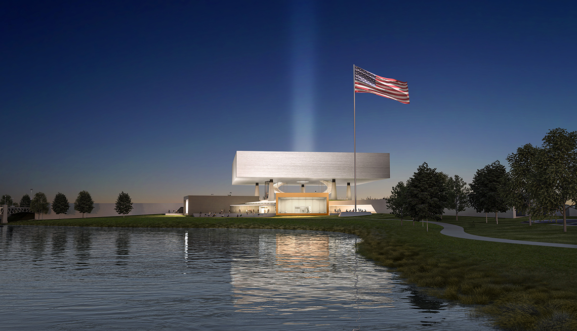 architect rendering of the future national medal of honor museum in arlington texas showing a view of the building from across a pond at night time