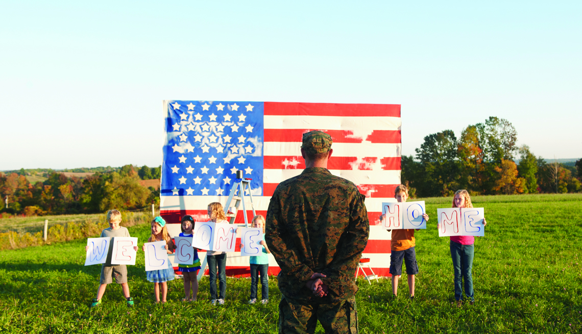 people hold up a welcome home sign as someone from the military stands before an american flag.