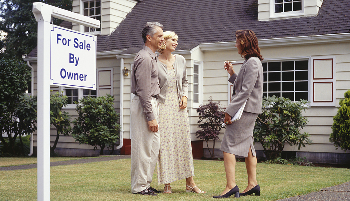 Couple talking to real estate agent on front lawn, sign in yard reads for sale by owner