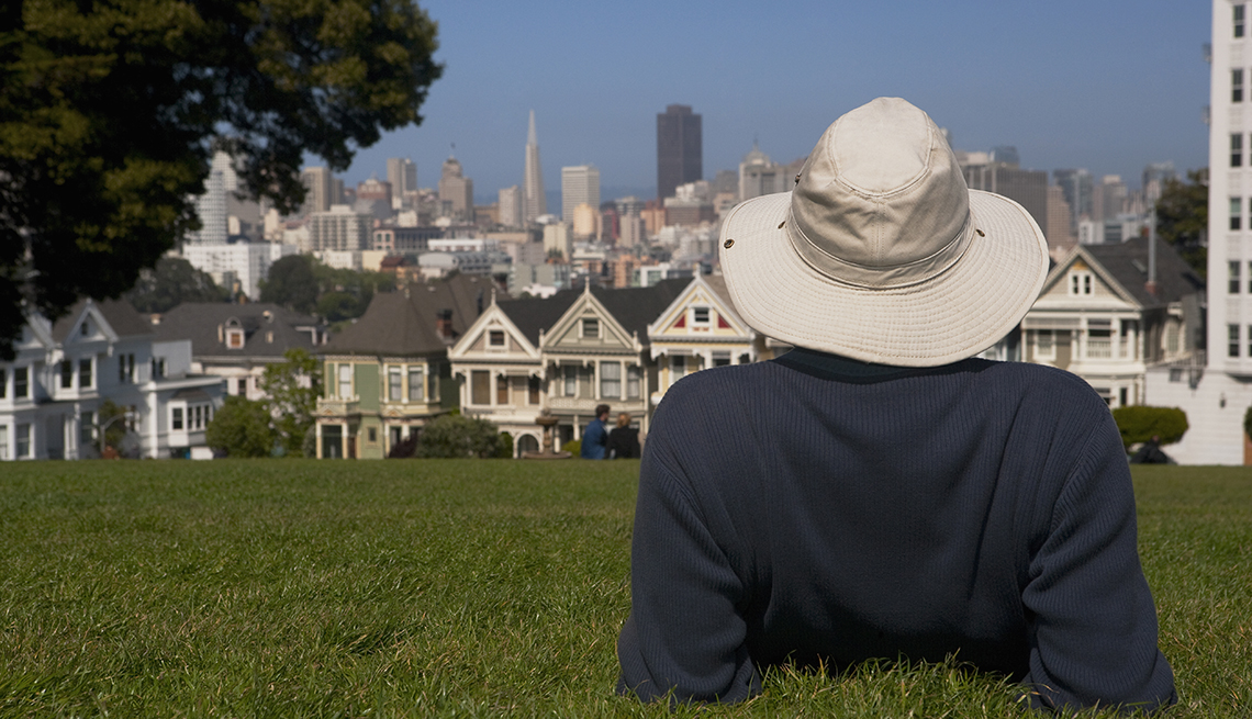 Un hombre acostado en un parque, con vista a la ciudad de San Francisco.